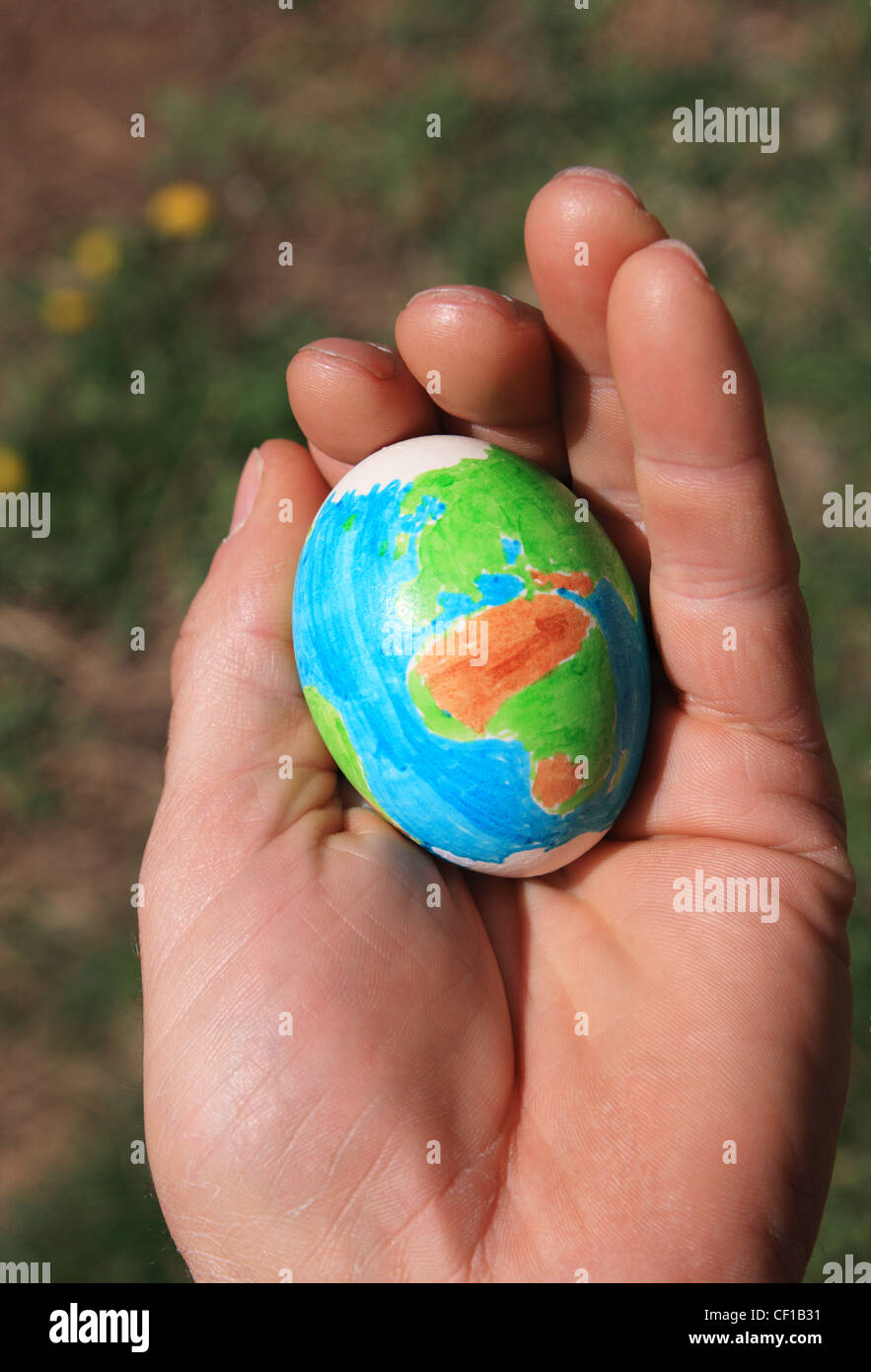 hand made Easter egg with a design of the earth held in a man's hand Stock Photo