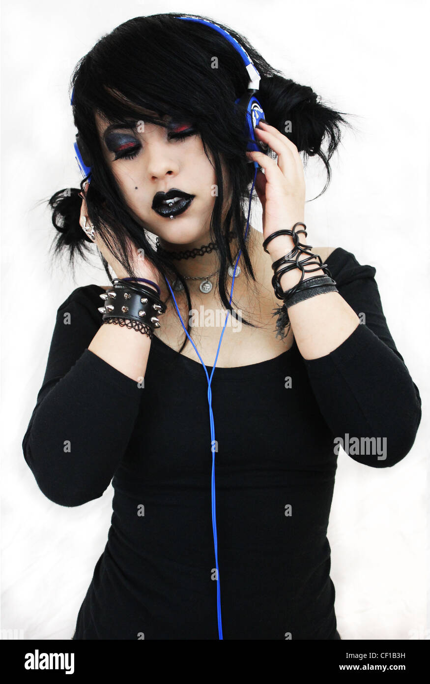 Young woman dressed in alternative fashion wearing blue headphones. Stock Photo