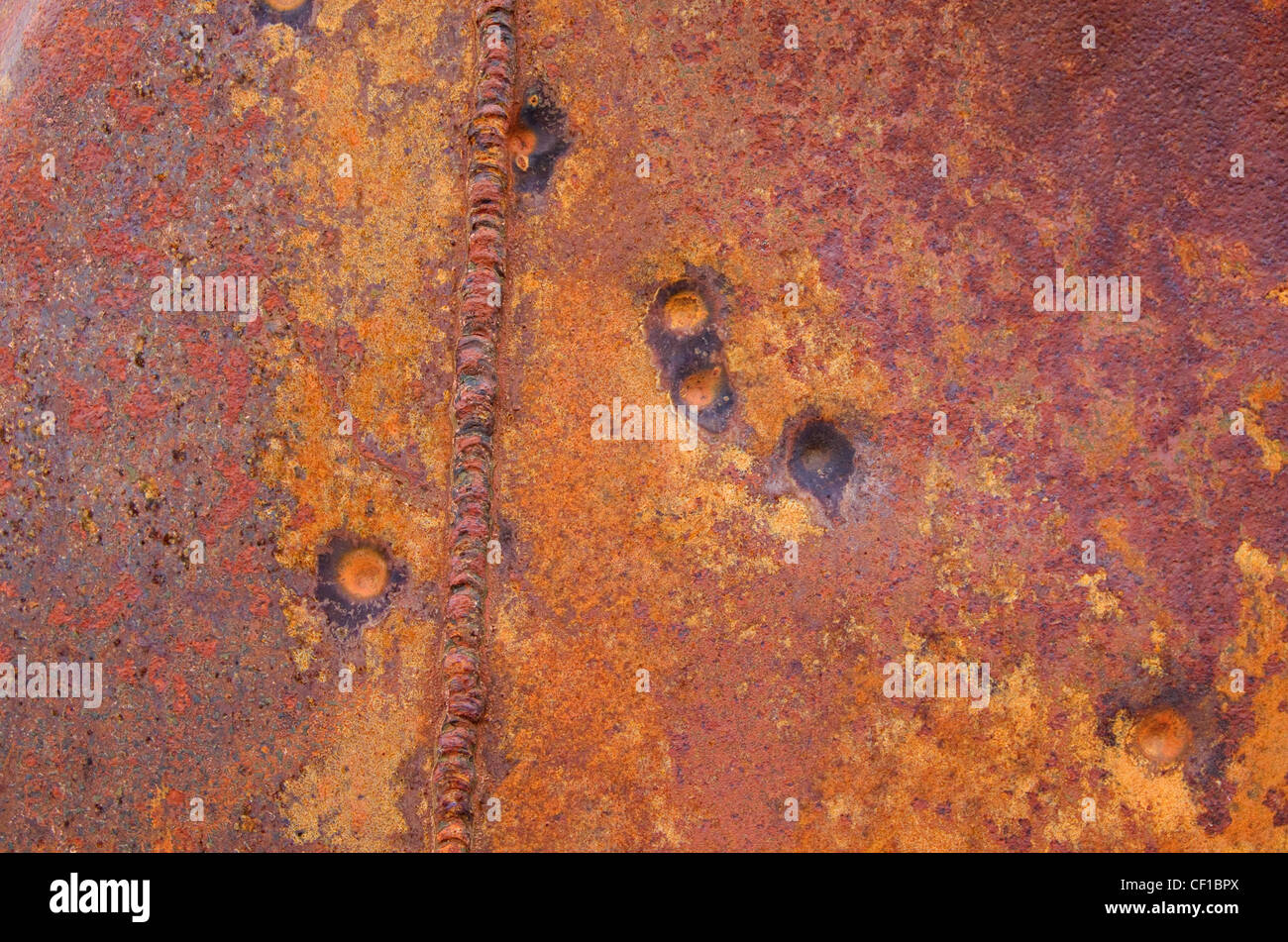 rusty sheet metal with a weld and some bullet impact spots Stock Photo