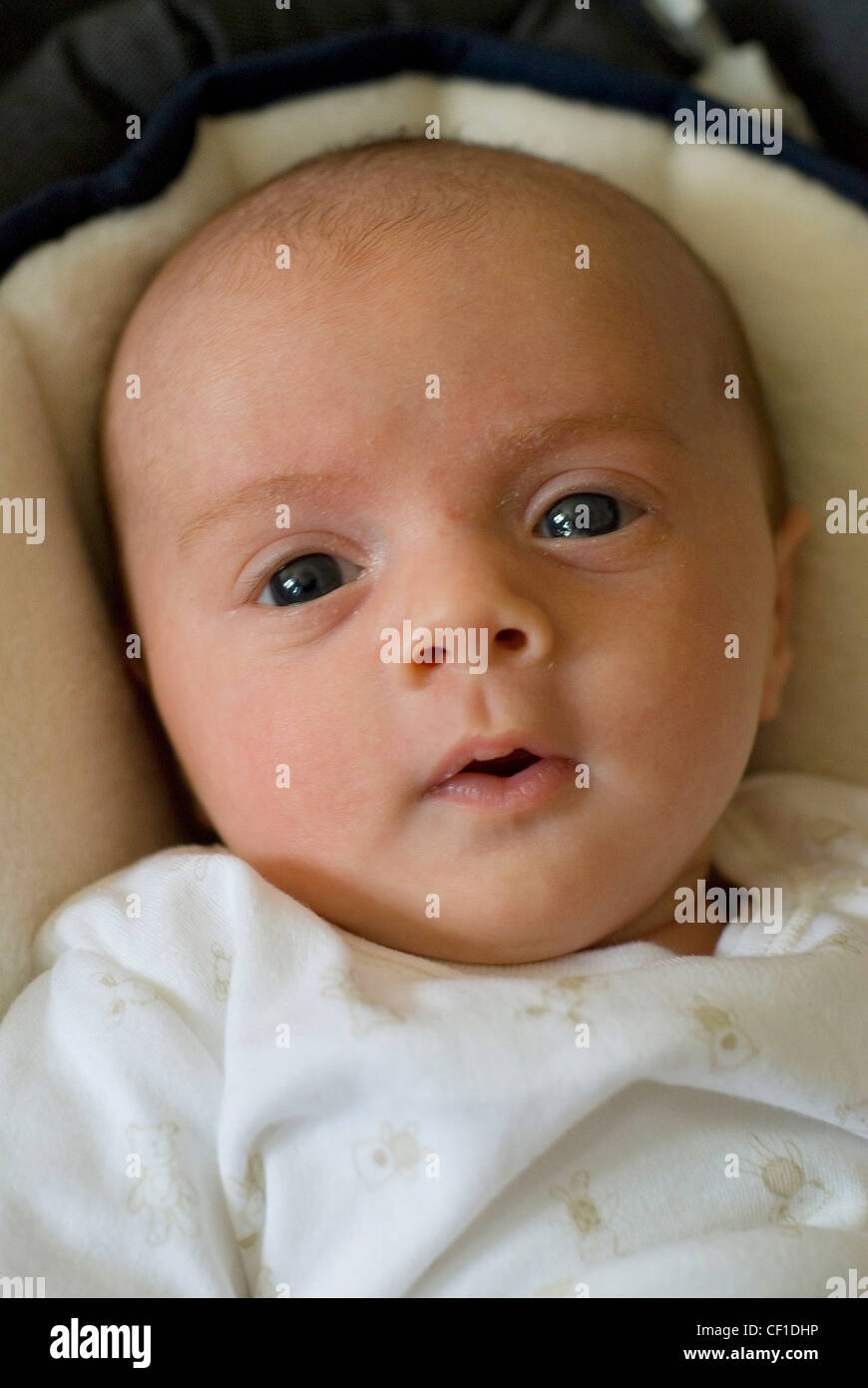 Female two month old baby dressed in a white patterned baby grown, with lips pursed Stock Photo