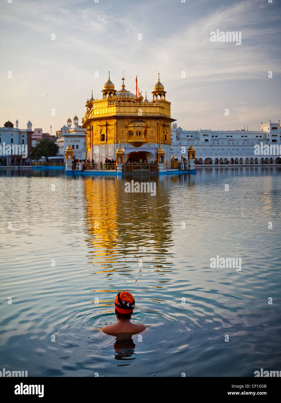 A Sikh man wearing a turban takes a bath in the pool surrounding the Golden Temple of Amritsar ...