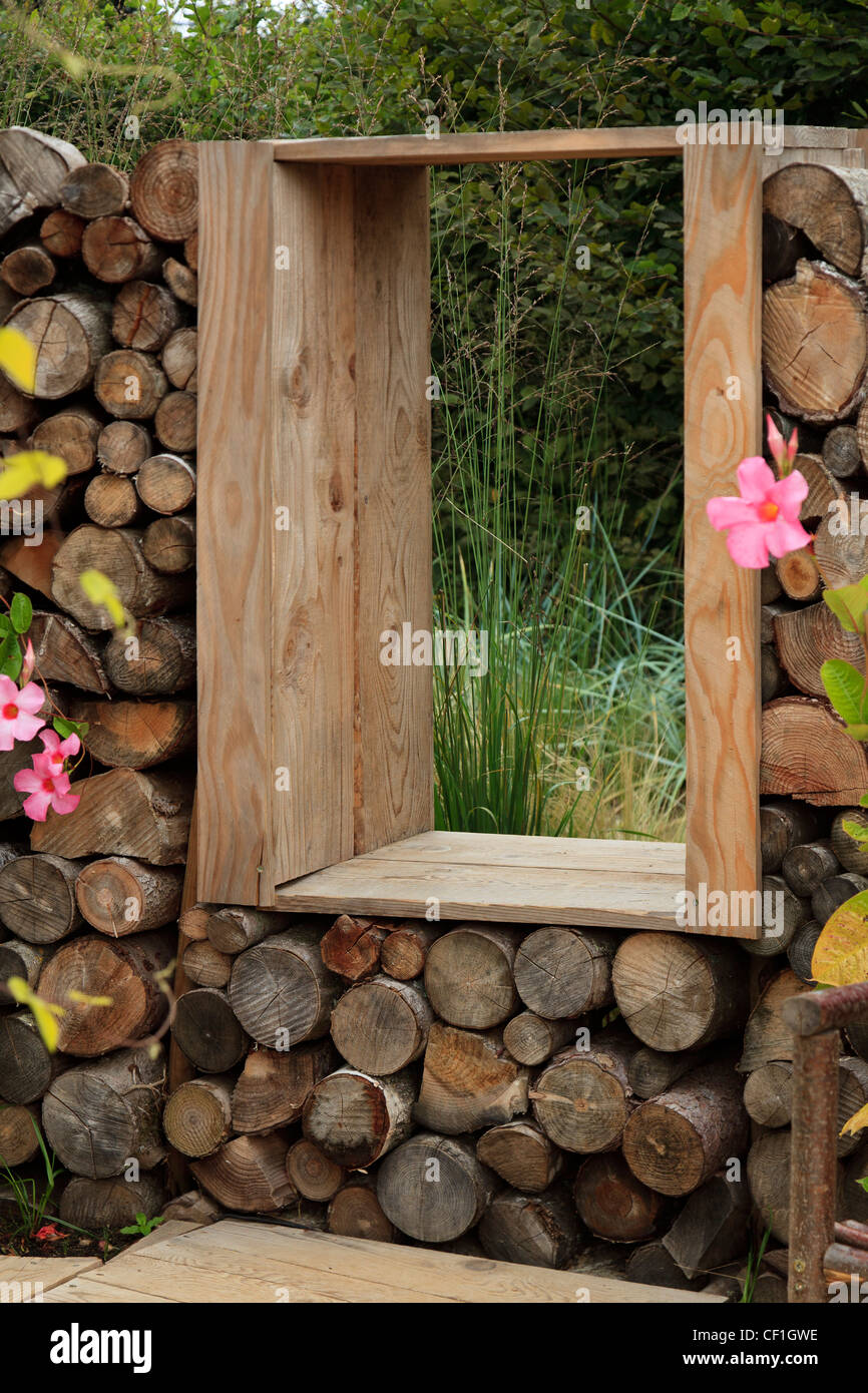 window in a wall made with logs. Festival International des Jardins de Chaumont-sur-Loire, : garden ' jardin de la terre gaste' Stock Photo