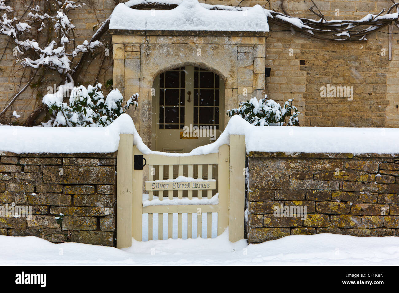 Snow covered gate and path leading to the front door of Silver Street House, a stone built Cotswold village house in South Cerne Stock Photo