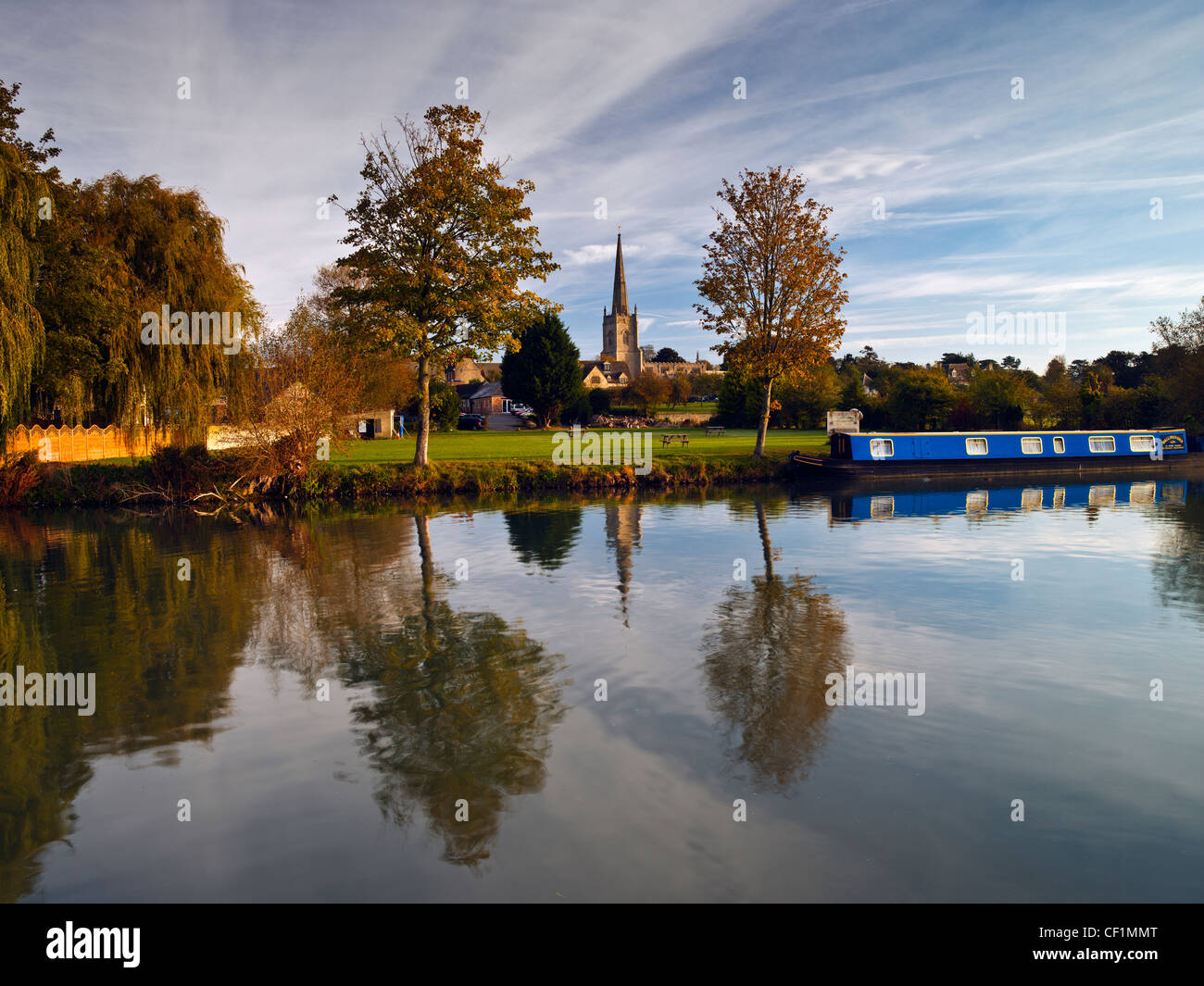 A narrow boat moored on the River Thames at Lechlade with St Lawrence church in the background. Stock Photo