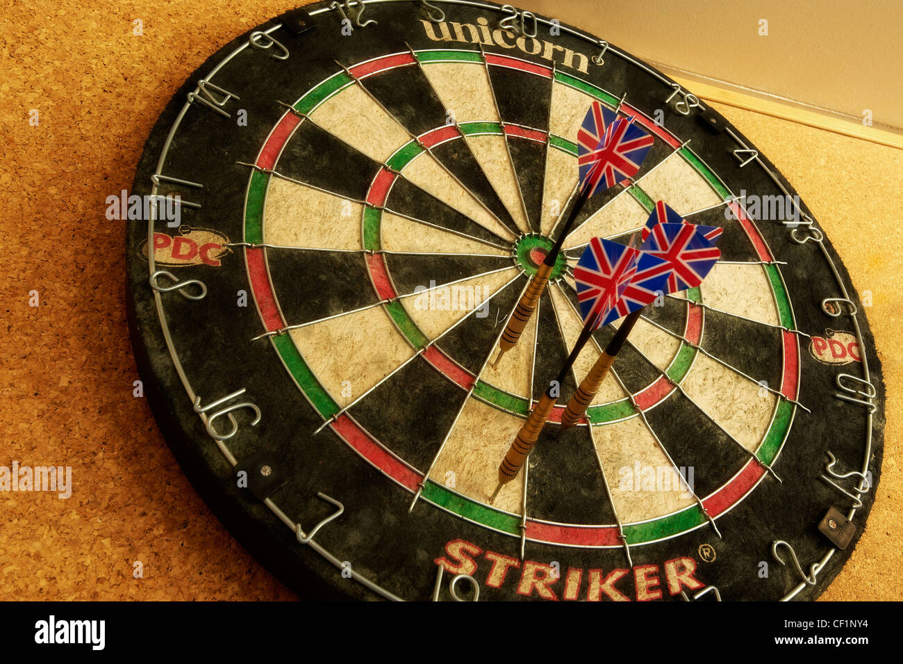 A close up of a traditional dartboard, with three darts with Union Jack