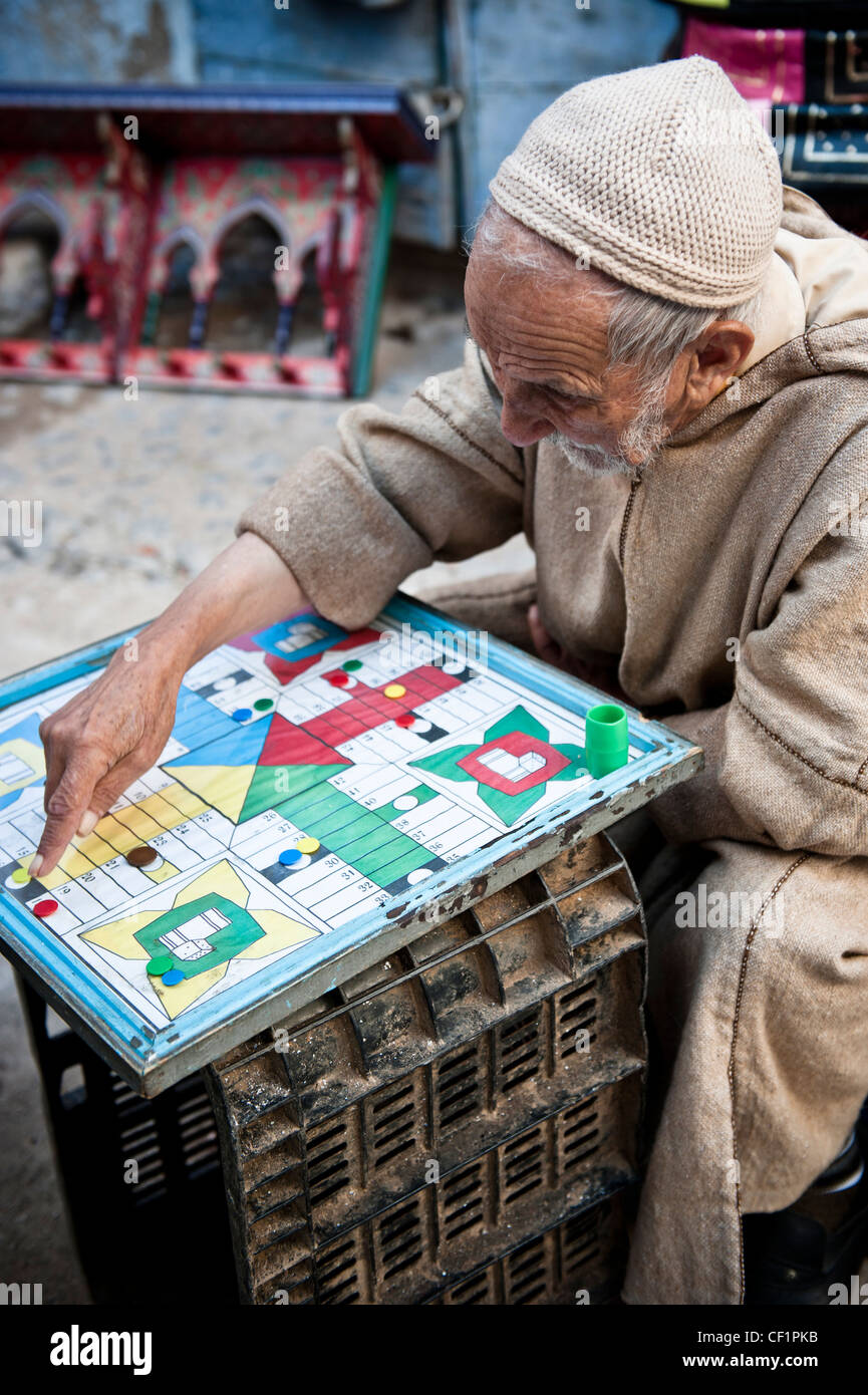 Old muslim man playing board games in streets of Chefchaouen, Morocco