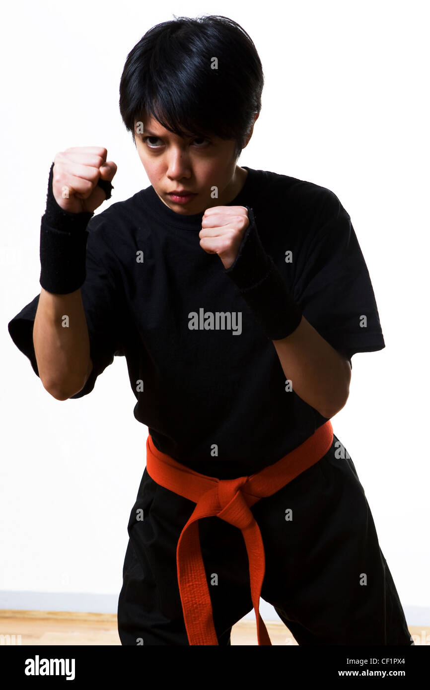 A young woman inside a studio in a martial arts fight wearing an orange