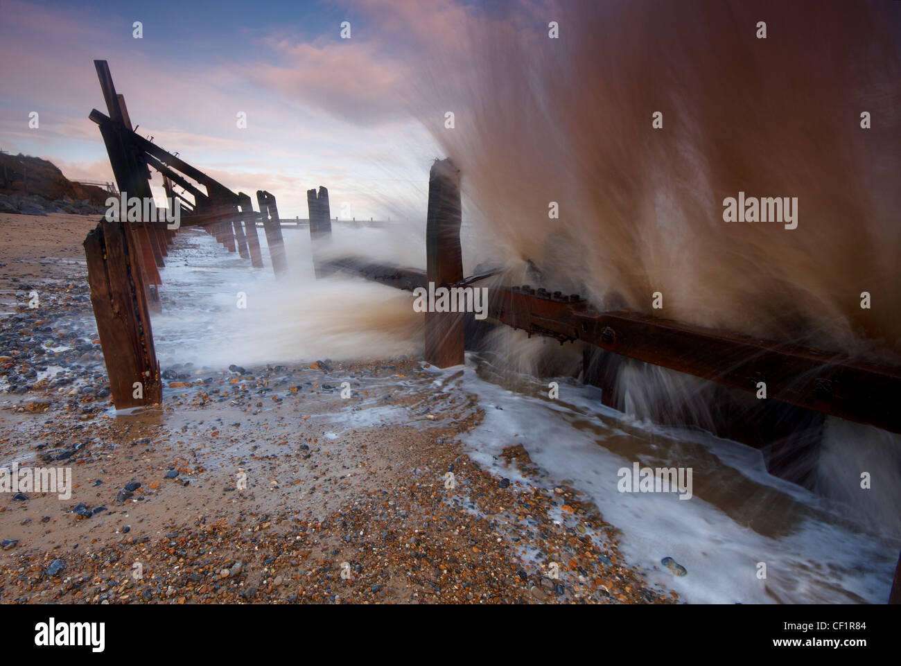 A wave breaking over coastal defences at Happisburgh on the Norfolk coast. Stock Photo