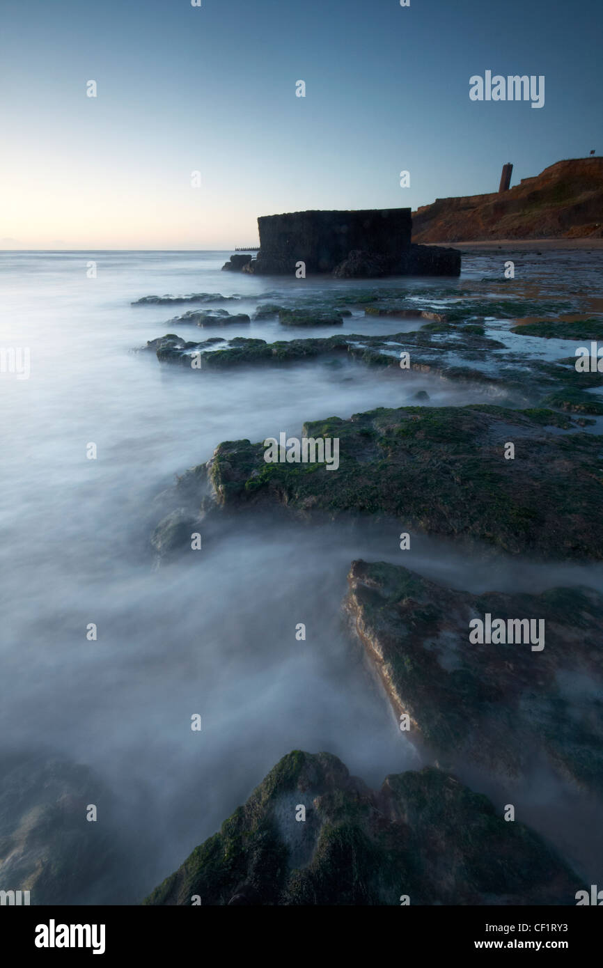 Waters swirling around a pillbox on the beach at the Naze in early dawn light. Stock Photo