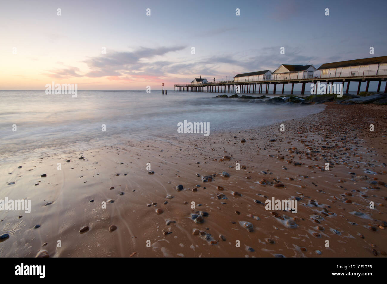 The tide ebbing from the beach by Southwold pier before sunrise. Stock Photo