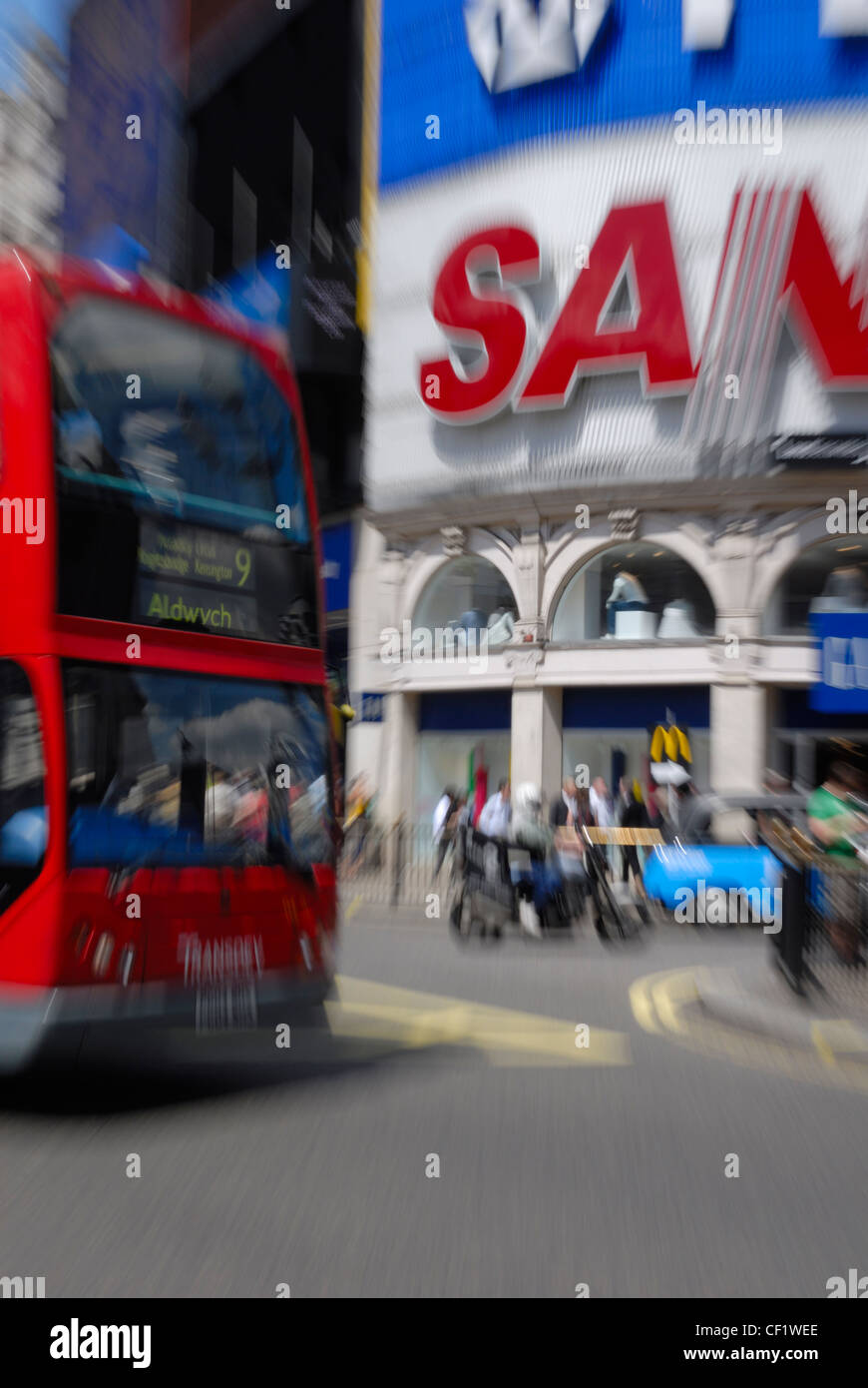 A red double decker bus driving past the iconic advertisements in Piccadilly Circus. Stock Photo