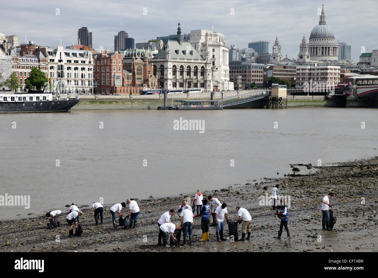 Volunteers cleaning litter from the Thames shore line on the South Bank at low tide. Stock Photo