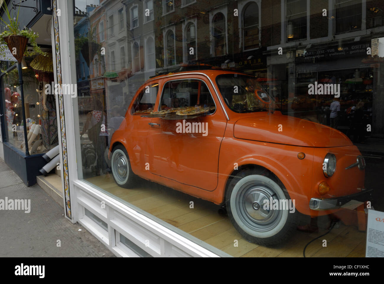 An iconic Fiat 500 car used to display pizzas in the window of a pizza restaurant in Notting Hill. Stock Photo