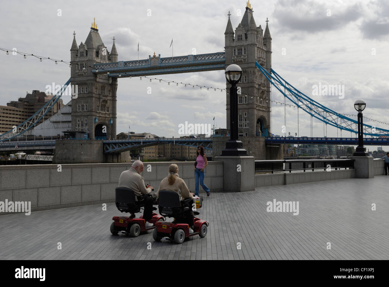 Elderly tourists using electric vehicles travelling along the embankment on the north side of the River Thames heading towards T Stock Photo