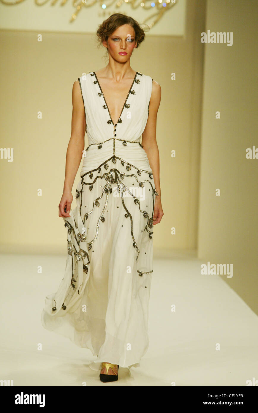 Temperley London Ready To Wear Spring Summer Model wearing ruched low cut  sleeveless white dress silver embroidery, looking to Stock Photo - Alamy