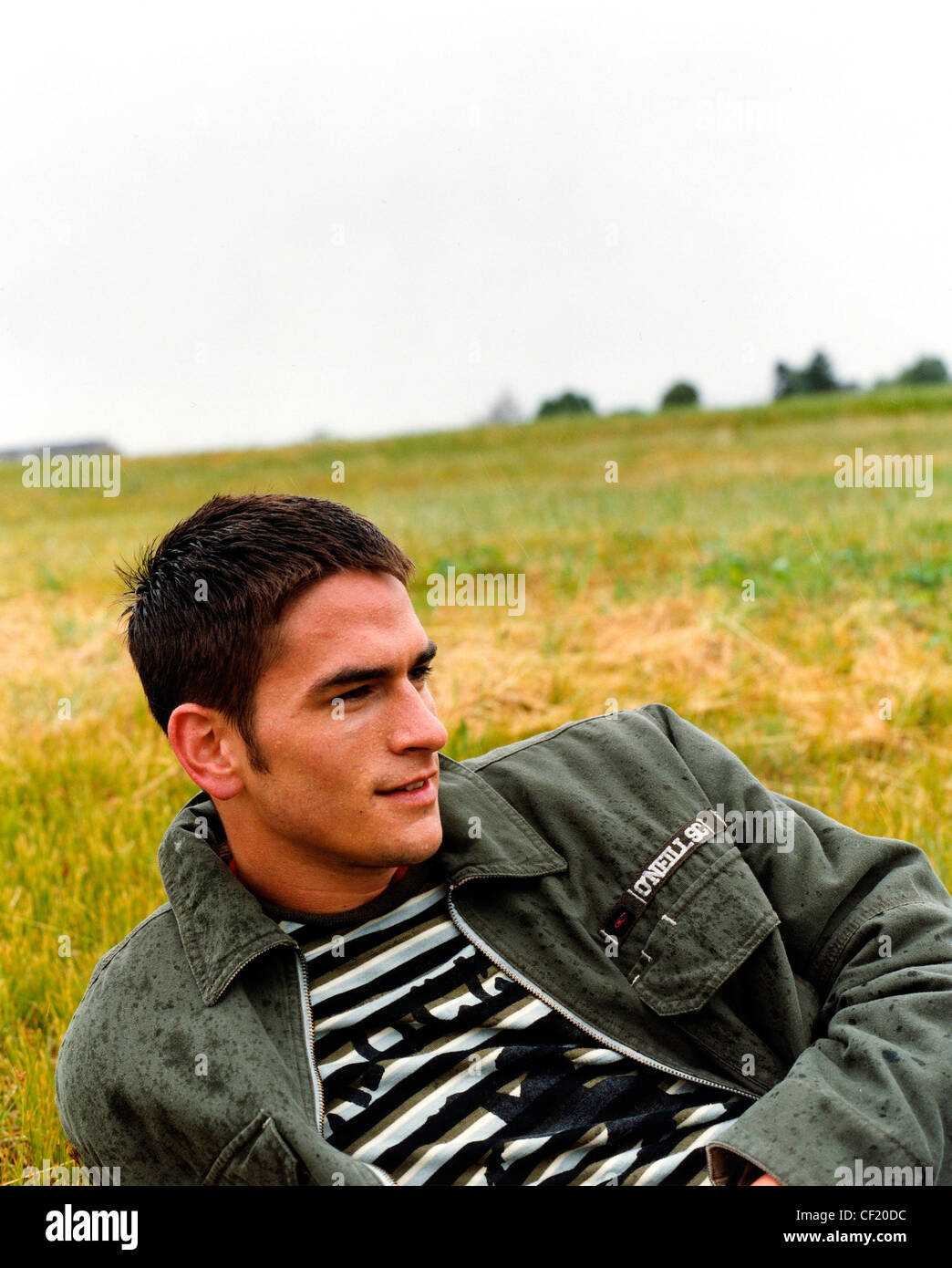 Male Short Brown Hair Lying On Grass In A Field In The Rain