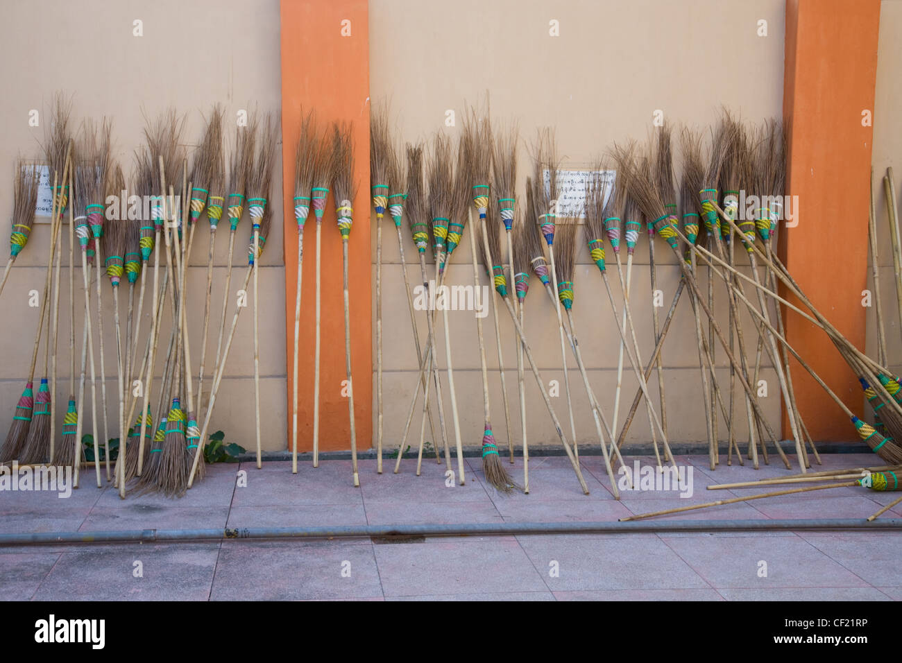 Old wooden brooms ready fly or sweep near wall in myanmar Stock Photo