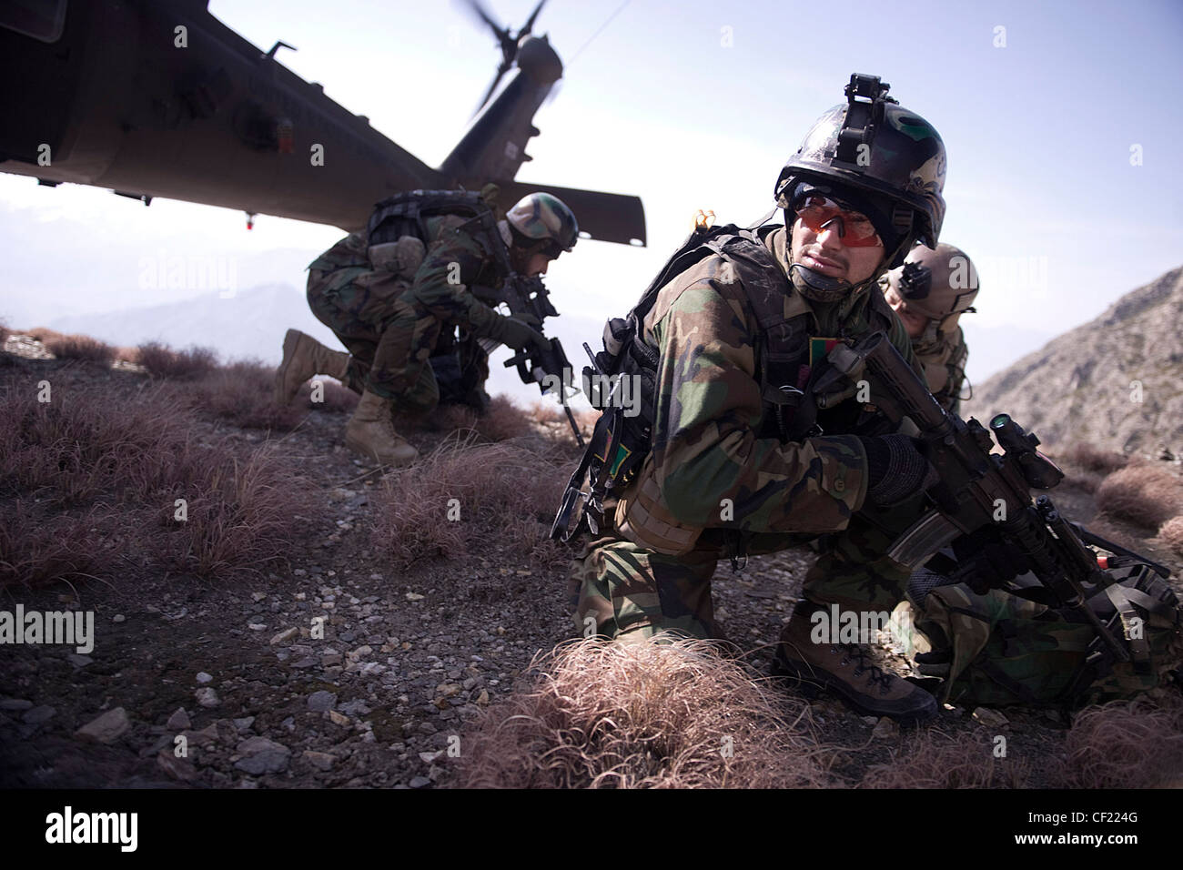 An Afghan National Army Commando dismounts a UH-60 Blackhawk helicopter during a mission in Kunar province, Afghanistan, Feb. 25. The commando-led mission conducted reconnaissance for a future Village Stability Platform, a site Afghan forces and coalition Special Operations Forces will use to live and work with villagers. Stock Photo