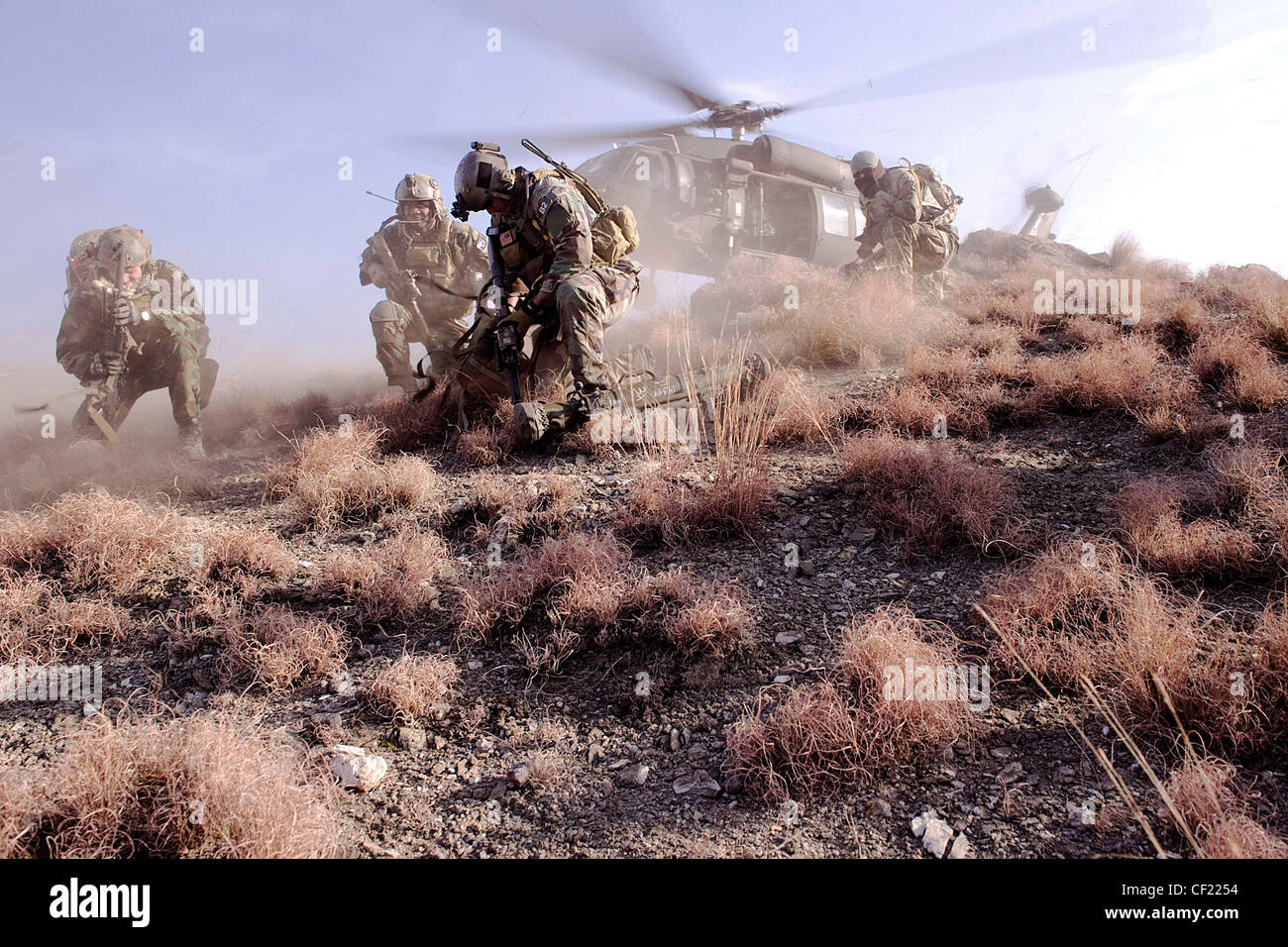 Coalition Special Operations Forces members cover their faces to avoid flying debris as they wait to board a UH-60 Blackhawk helicopter during a mission in Kunar province, Afghanistan, Feb. 25. The commando-led mission conducted reconnaissance for a future Village Stability Platform, a site Afghan forces and coalition SOF will use to live and work with villagers. Stock Photo