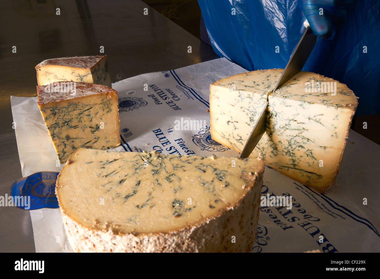 A whole blue stilton cheese being cut into smaller blocks. Stock Photo