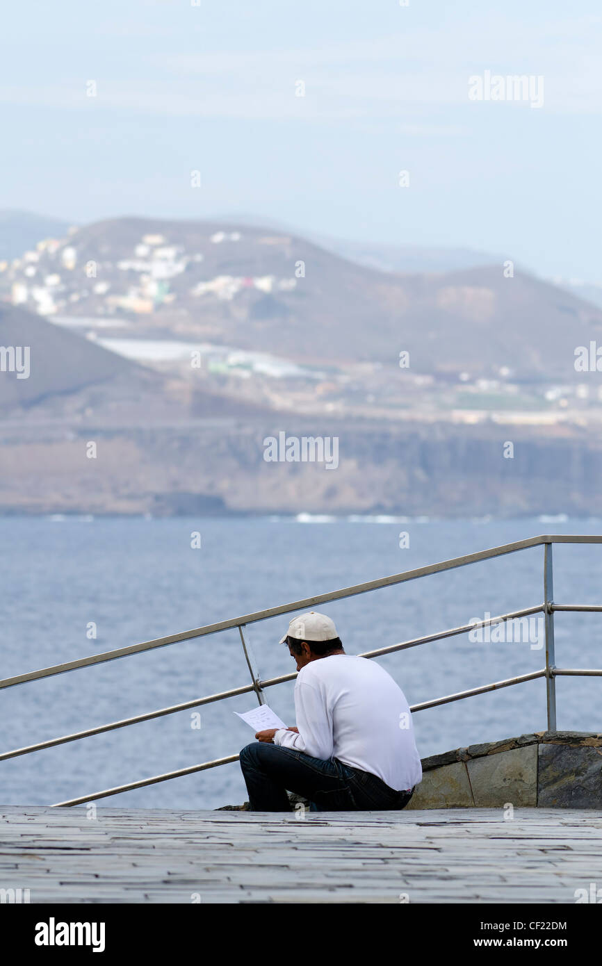 a man reading next to the sea Stock Photo