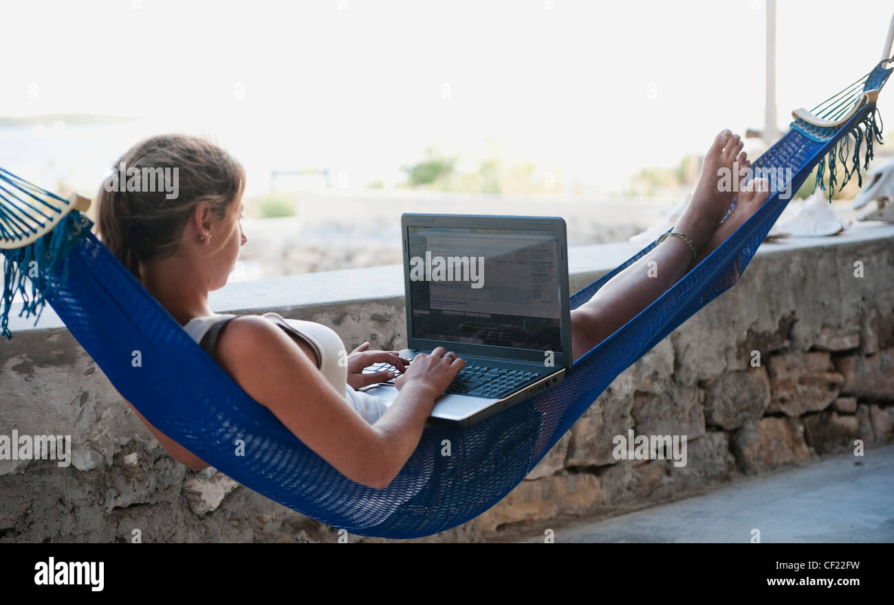 Girl Working On A Laptop While Laying In A Hammock; South Caicos Turks And Caicos Islands Stock Photo