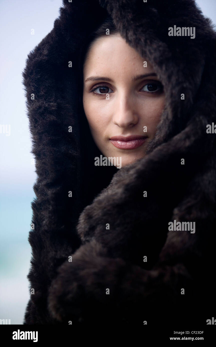 Female with hair off face wearing black fur coat and hood
