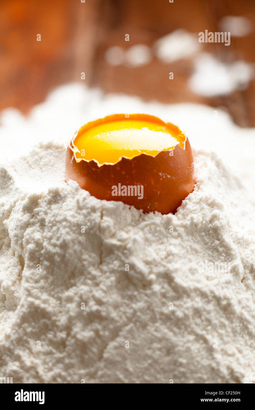 Opened Egg Shell with Yolk on Flour Stock Photo