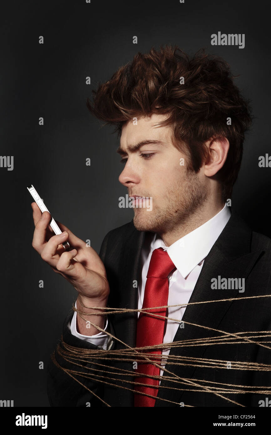 low key image of businessman on a mobile phone all tied up Stock Photo