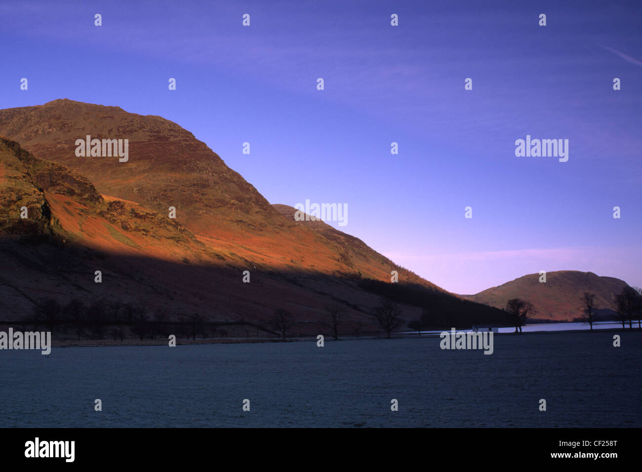 Early morning light illuminates the hills surrounding Lake Buttermere and Peggys Bridge. Stock Photo