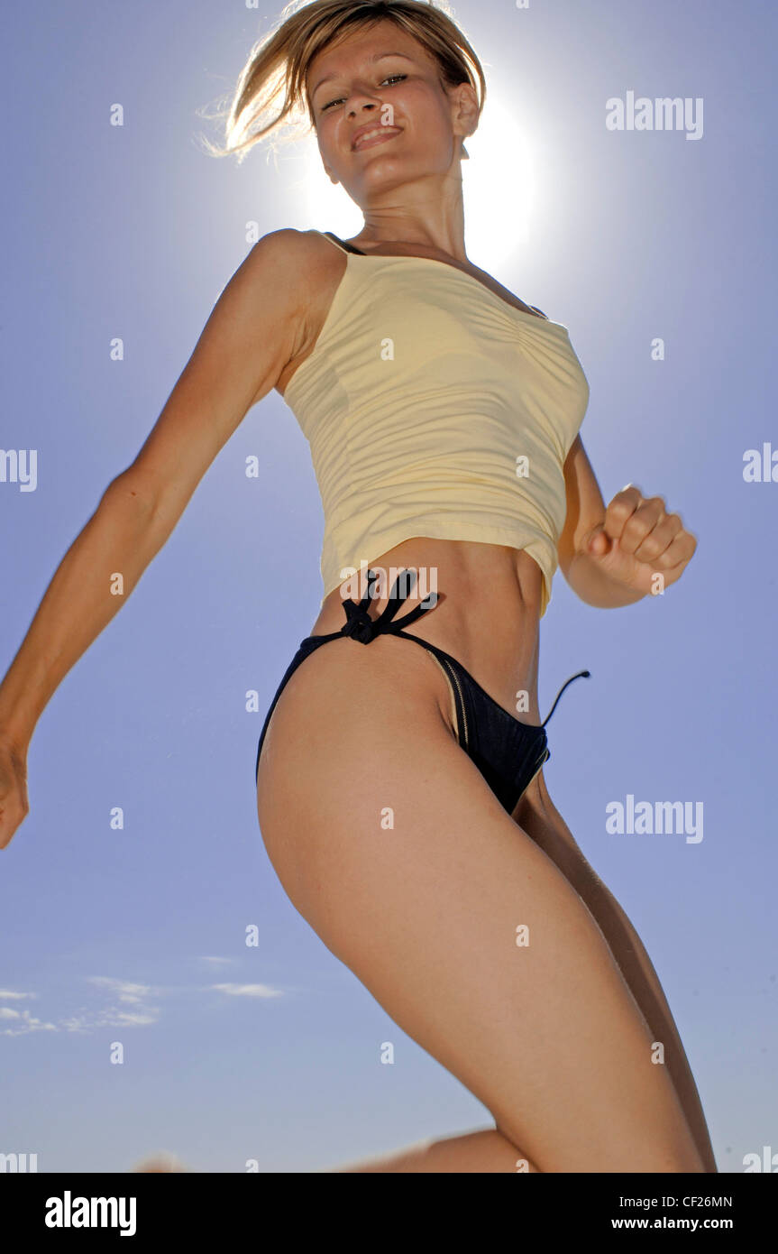 Female, short blonde hair, yellow vest top, black tie string bikini,  jumping in air Stock Photo - Alamy