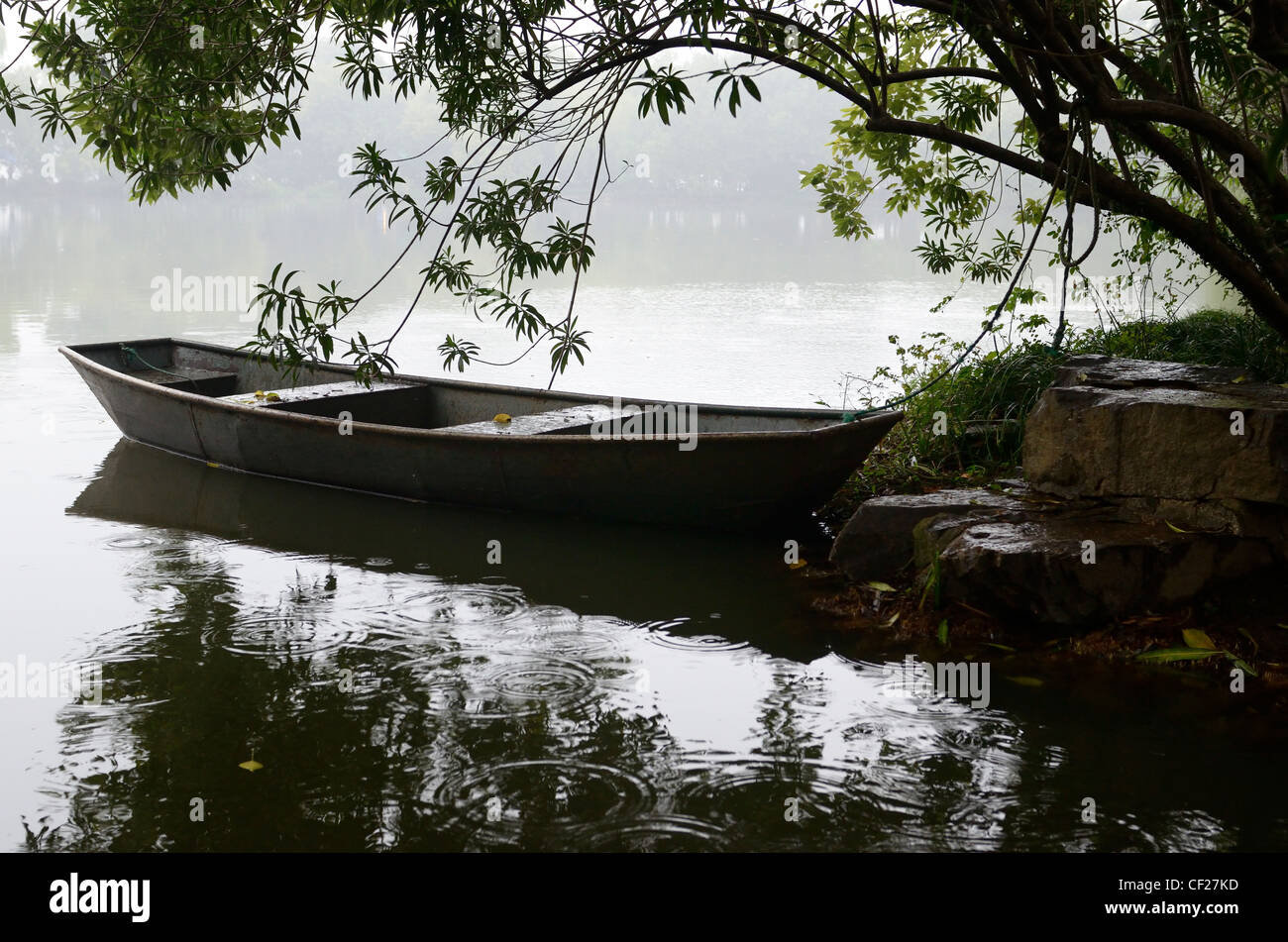 Steel boat in rain moored at Three Pools Mirroring the Moon Island West Lake Hangzhou Peoples Republic of China Stock Photo