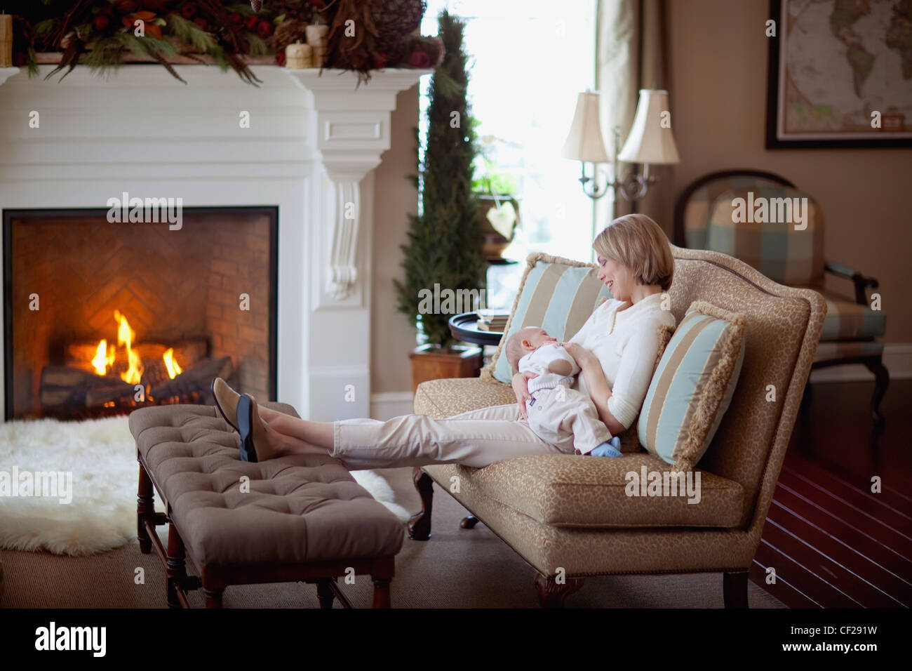 A Mother Holding Her Baby By A Fireplace In The Living Room; Jordan Ontario Canada Stock Photo