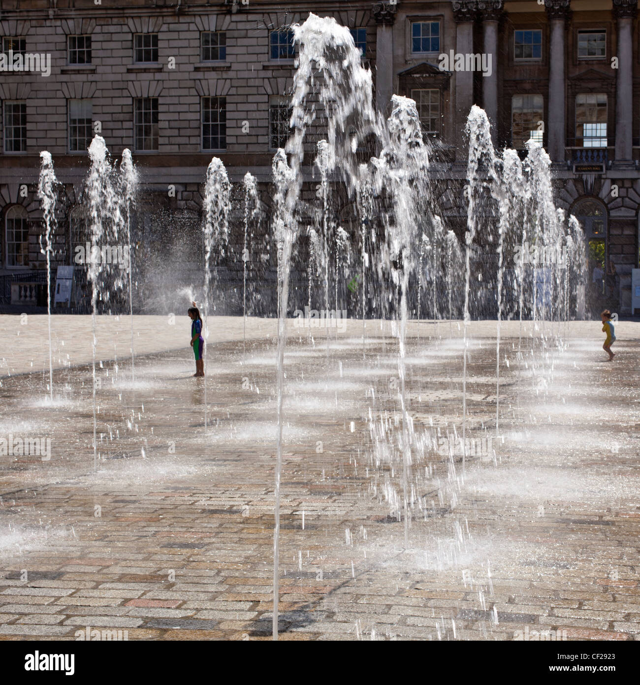 Children standing under fountains in the Edmond J. Safra Fountain Court at Somerset House. Stock Photo