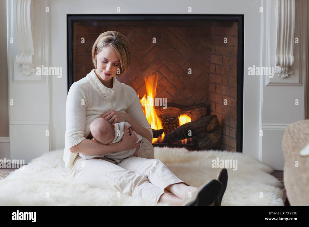 Mother Breastfeeding Baby By Fireplace; Jordan Ontario Canada Stock Photo