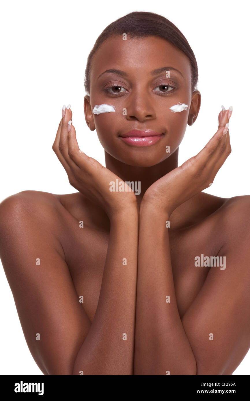 Skincare - Young naked ethnic African-American woman with slicked back hair applying cream moisturizer on her face after sauna Stock Photo