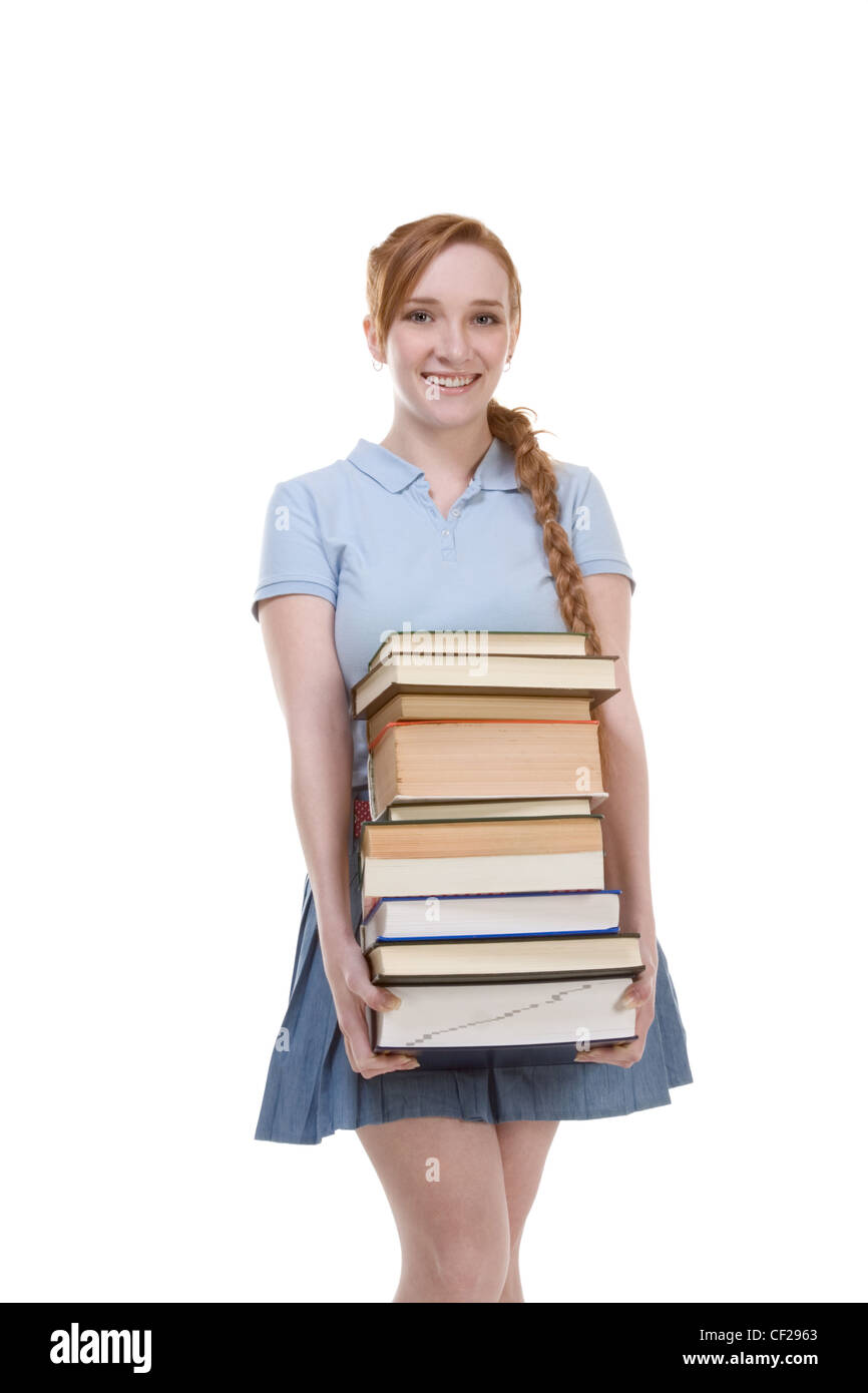 Young Caucasian female college student in jeans with backpack holding huge pile of educational books from library Stock Photo