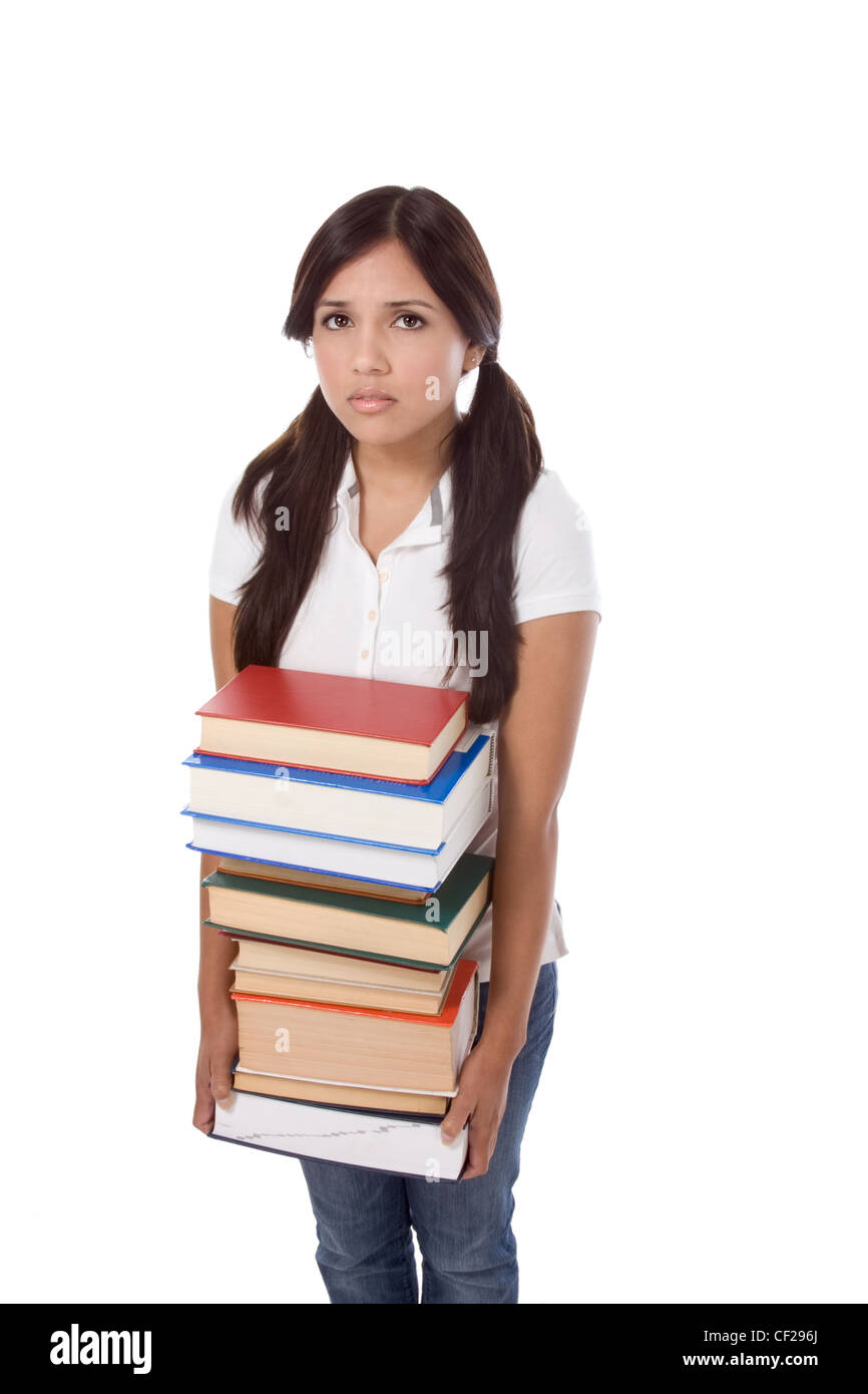 Young Hispanic female college student in jeans holding huge pile of educational books from library Stock Photo