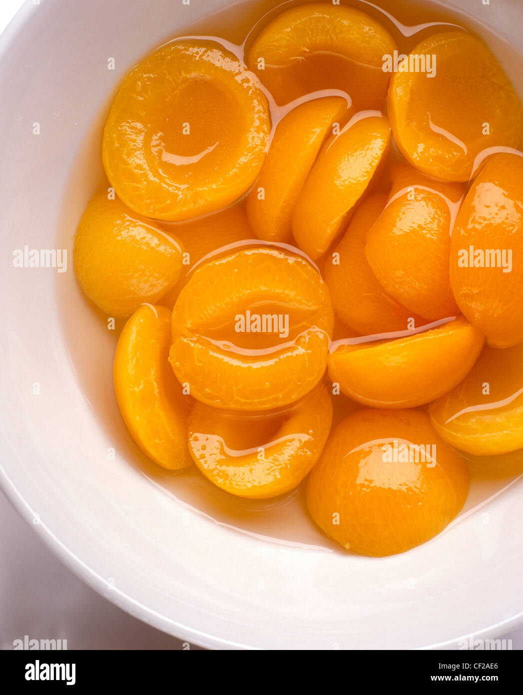 A still life bowl of tinned apricot halves in syrup Stock Photo