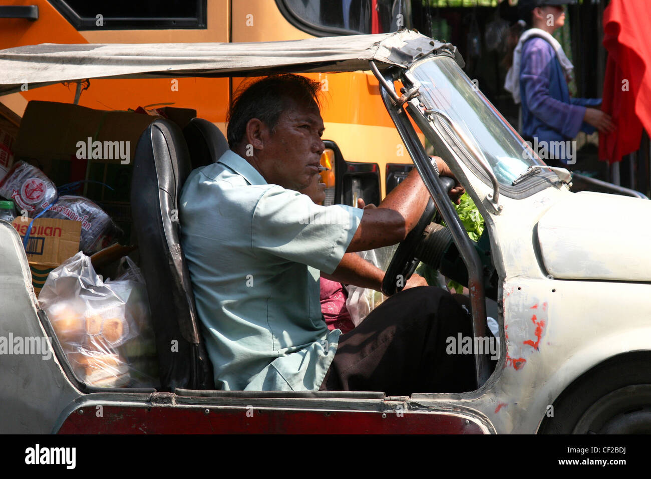 A man is driving a fully loaded old jalopy (car) on a city street in Bangkok, Thailand. Stock Photo