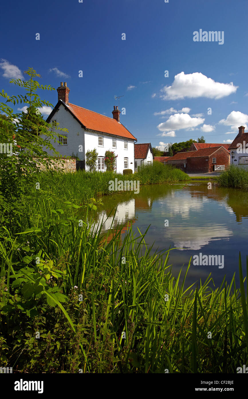 Cottages reflected in the village pond at Burton Stock Photo Alamy