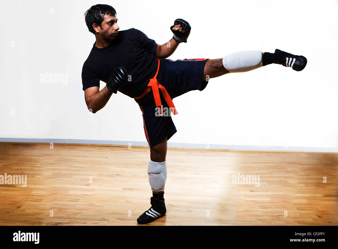 A man inside a studio in a practicing a martial arts move wearing