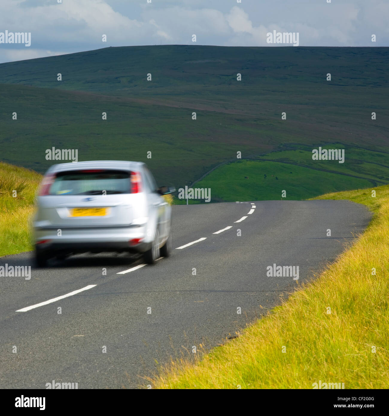A car travelling along a country road running through dramatic Pennine scenery, in the North Pennines Area of Outstanding Beauty Stock Photo