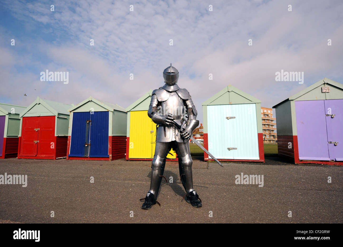 Man wearing suit of armor armour on Brighton seafront by beach huts Stock Photo