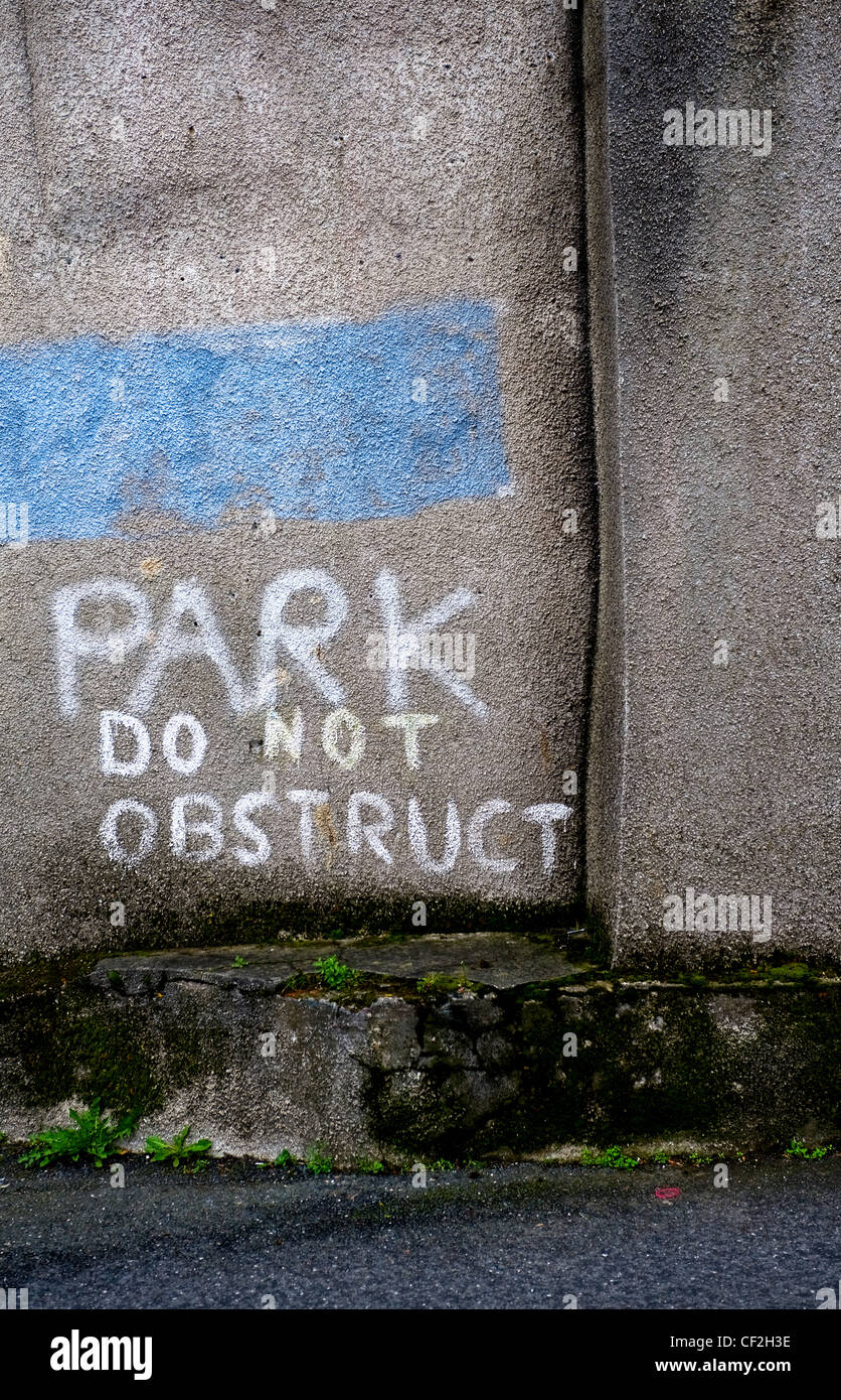 'Park' written on a wall contrary to the 'Do Not Obstruct' message below. Stock Photo