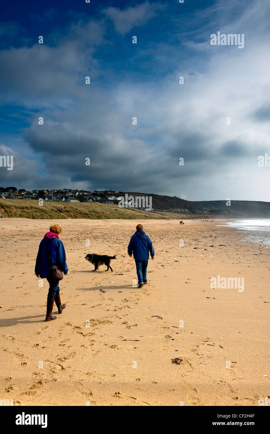A couple walking their dog on Praa Sands. Stock Photo
