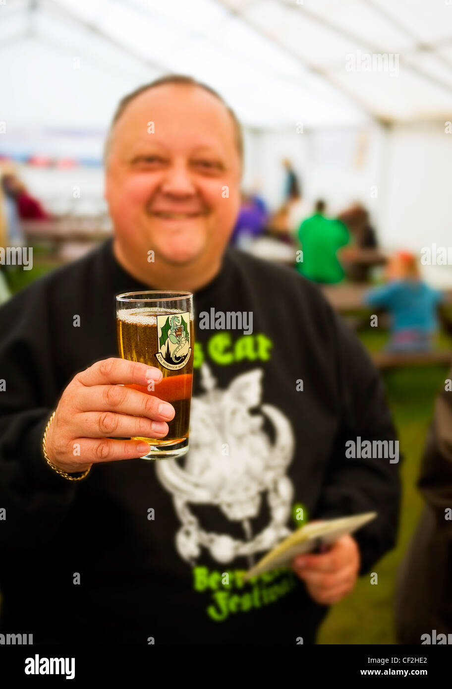 A man holding up a pint of real ale inside a marquee at the Hoop Beer Festival. Stock Photo