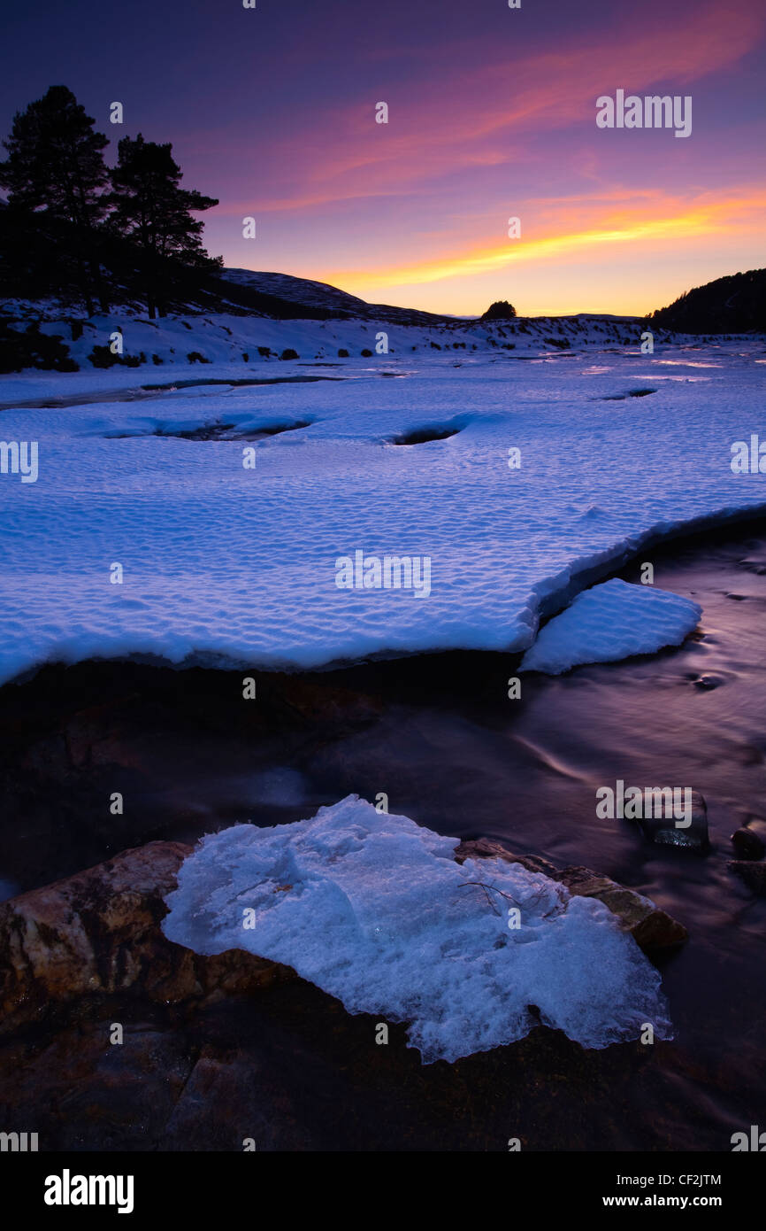 Pink sunset over the ice covered River Dee near the bridge over the Linn of Dee. Stock Photo