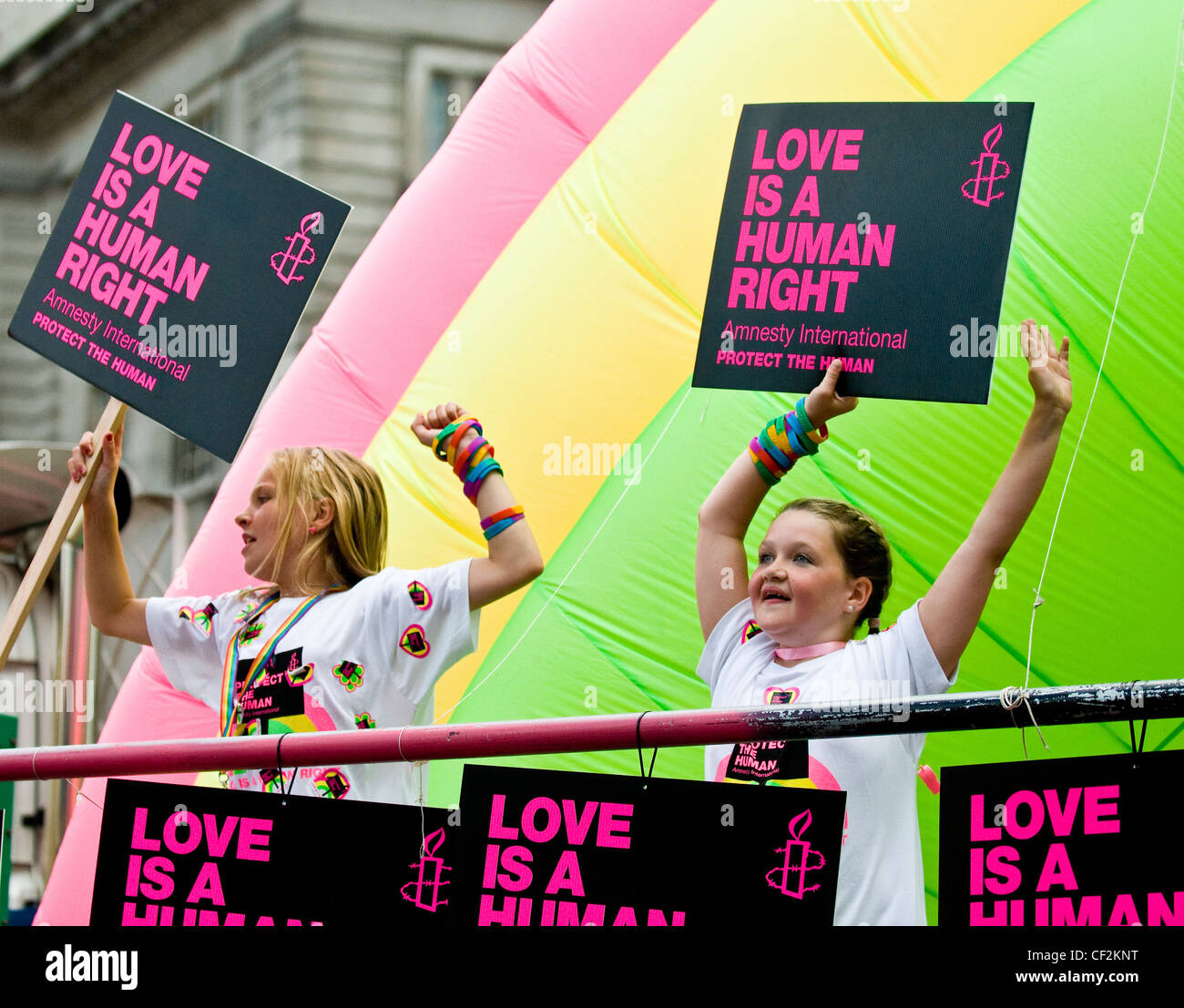 Two young girls holding Amnesty International placards stating 'Love is a Human Right' at the Pride London parade. Stock Photo