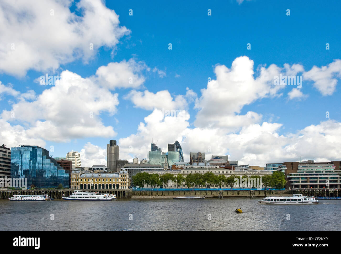A sightseeing cruise boat travelling along the River Thames past some iconic London landmarks on the City of London skyline. Stock Photo